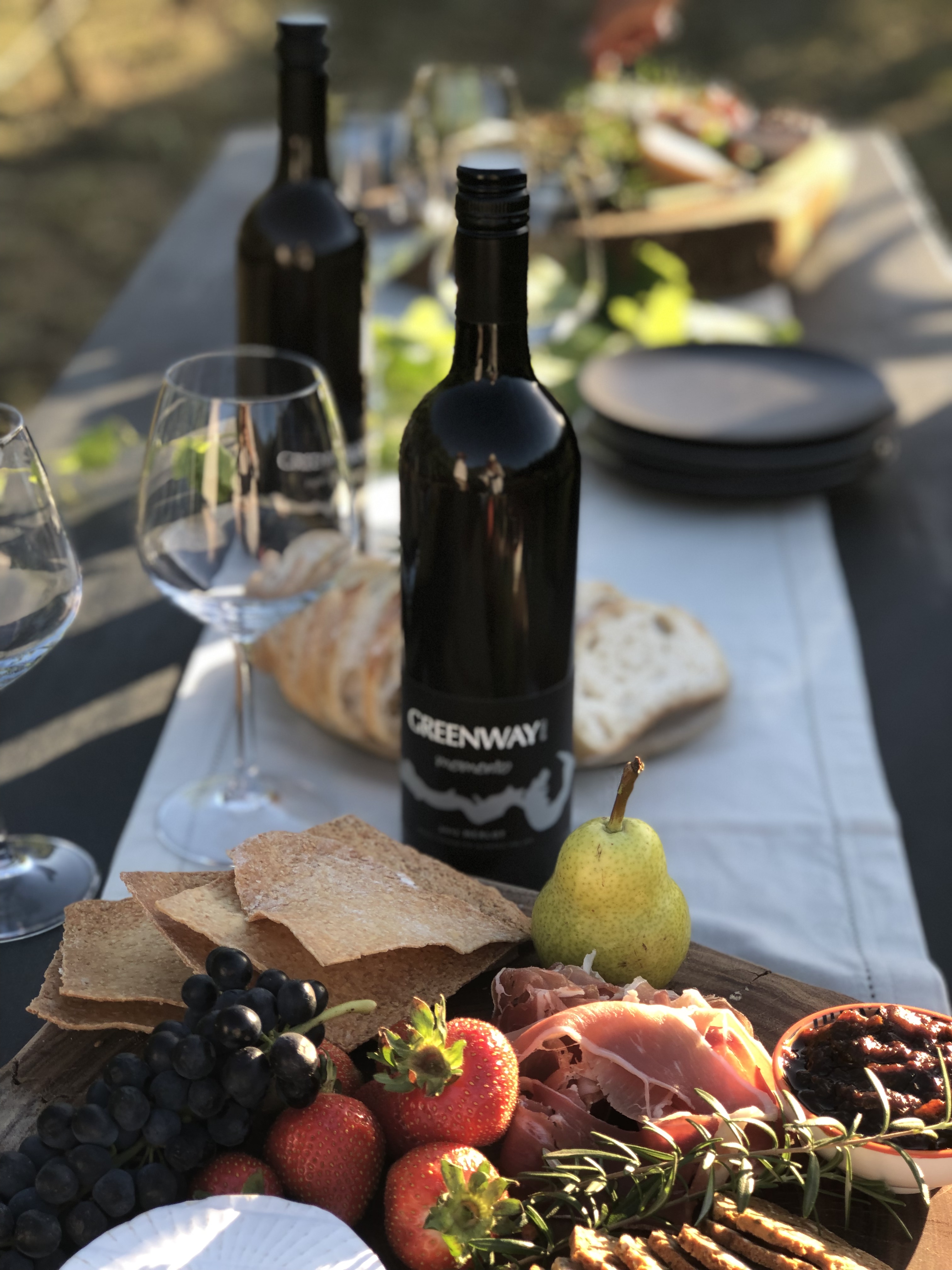 Two wines bottles with food on table outside 